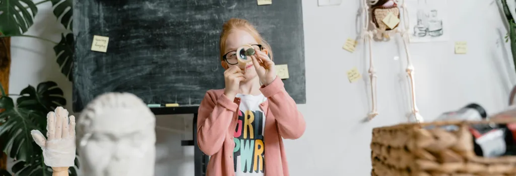 A young student inspecting something with a magnifying glass